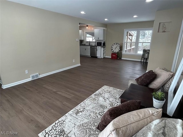 living room featuring a wealth of natural light, dark wood-type flooring, and sink