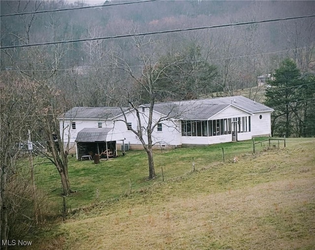 view of front facade with a sunroom and a front lawn