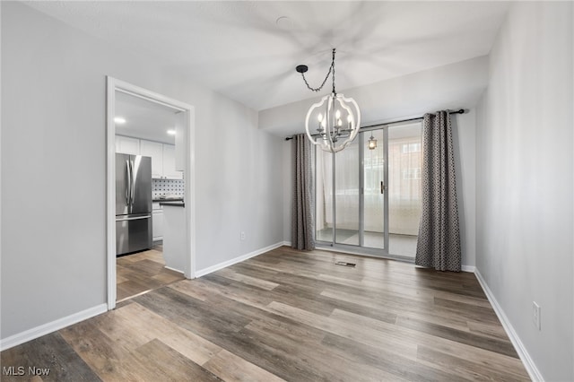 unfurnished dining area featuring hardwood / wood-style floors and an inviting chandelier