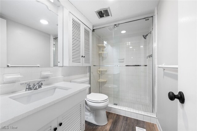 bathroom with walk in shower, wood-type flooring, toilet, vanity, and tile walls