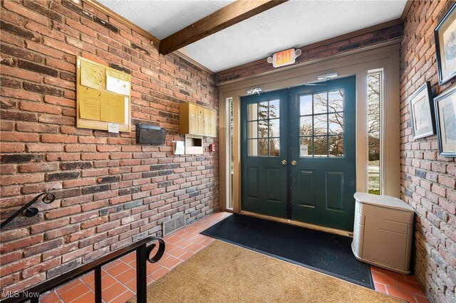 carpeted foyer entrance featuring beam ceiling, brick wall, and a textured ceiling