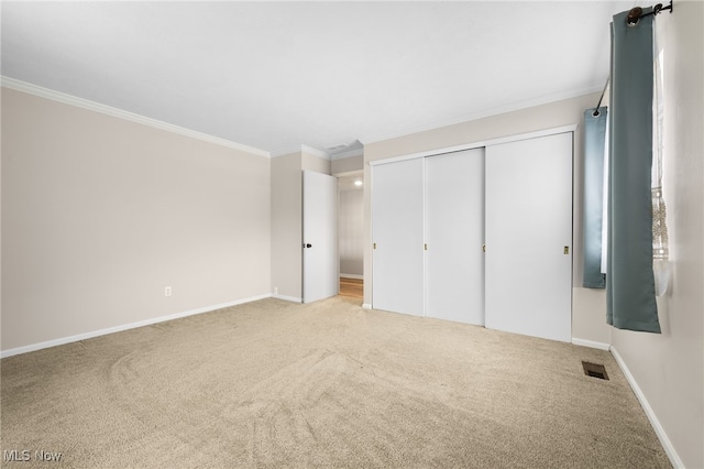 unfurnished bedroom featuring crown molding, light carpet, and a closet