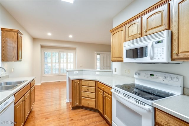 kitchen with kitchen peninsula, light hardwood / wood-style floors, white appliances, and sink