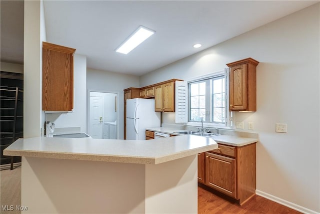 kitchen with sink, washing machine and dryer, kitchen peninsula, stove, and white fridge