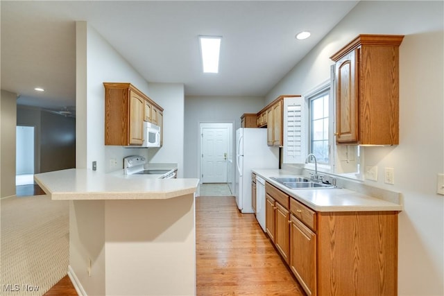 kitchen featuring a kitchen bar, sink, white appliances, and kitchen peninsula