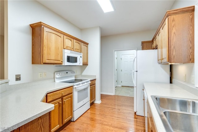 kitchen with light hardwood / wood-style floors, white appliances, and sink