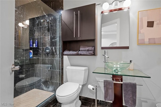 bathroom with a tile shower, vanity, and toilet