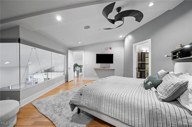 bedroom featuring light hardwood / wood-style flooring, ensuite bath, and lofted ceiling