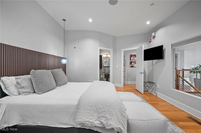 bedroom with connected bathroom and hardwood / wood-style flooring