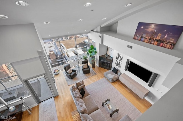 living room with a fireplace, light hardwood / wood-style floors, and expansive windows