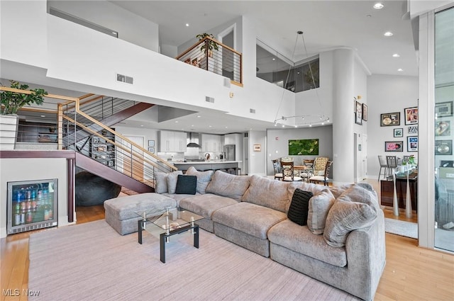 living room with light hardwood / wood-style floors and a towering ceiling