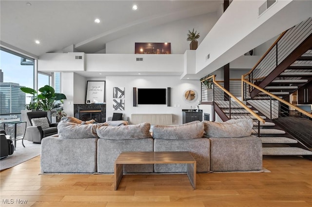 living room featuring a premium fireplace, light hardwood / wood-style flooring, and a high ceiling