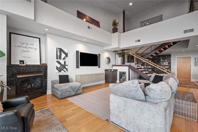 living room featuring hardwood / wood-style floors, a premium fireplace, and a high ceiling