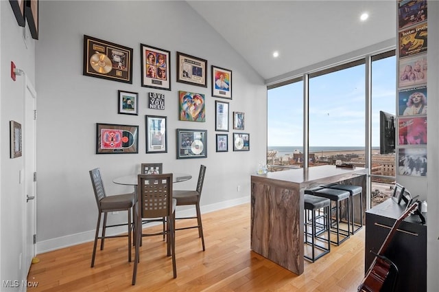 dining area with expansive windows, light hardwood / wood-style floors, and vaulted ceiling