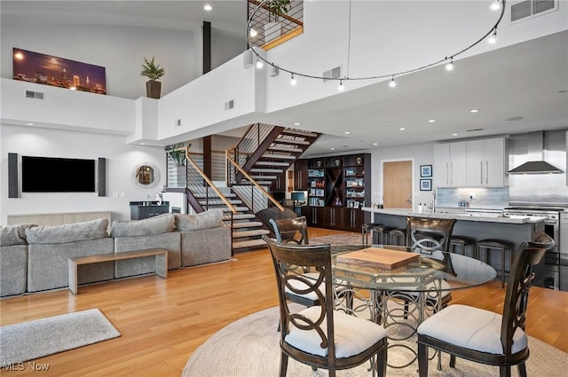 dining area with light hardwood / wood-style flooring and a towering ceiling