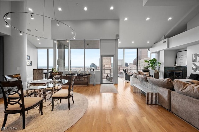 dining room featuring expansive windows, a high ceiling, a high end fireplace, and light hardwood / wood-style flooring