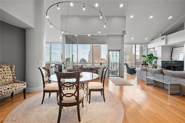 dining room with light wood-type flooring, expansive windows, and a premium fireplace