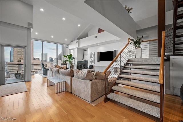 living room with a wood stove, high vaulted ceiling, and light hardwood / wood-style floors