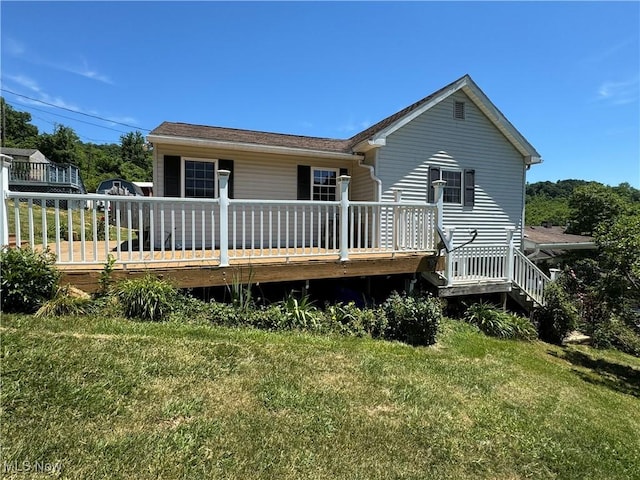 rear view of property featuring a yard and a wooden deck