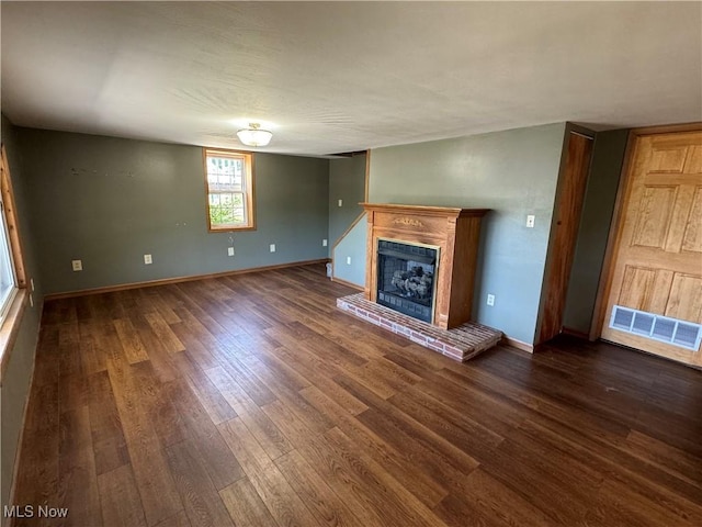 unfurnished living room with dark hardwood / wood-style floors and a brick fireplace