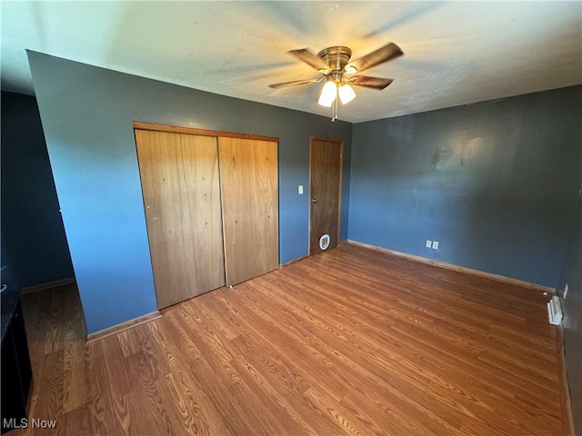 unfurnished bedroom with wood-type flooring, a closet, and ceiling fan