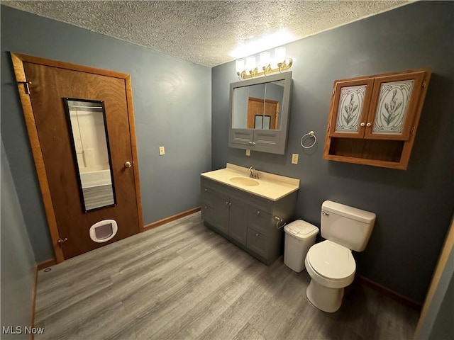 bathroom with vanity, toilet, wood-type flooring, and a textured ceiling