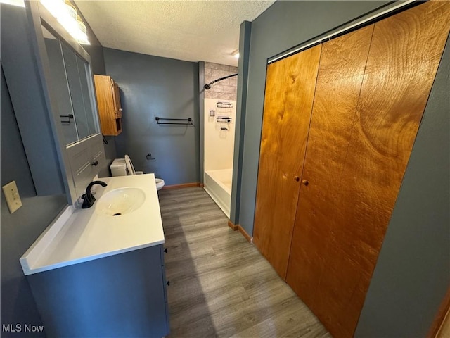 bathroom with hardwood / wood-style floors, vanity, a textured ceiling, and toilet