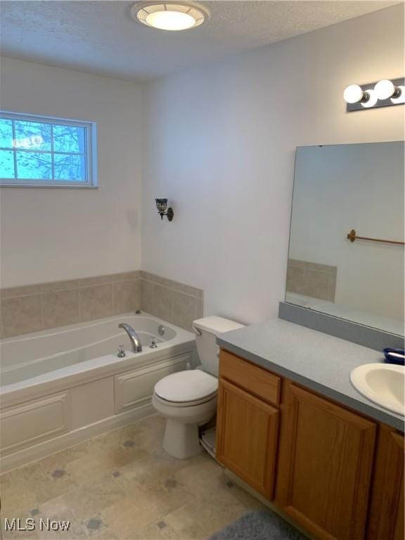 bathroom featuring vanity, a bathtub, toilet, and a textured ceiling