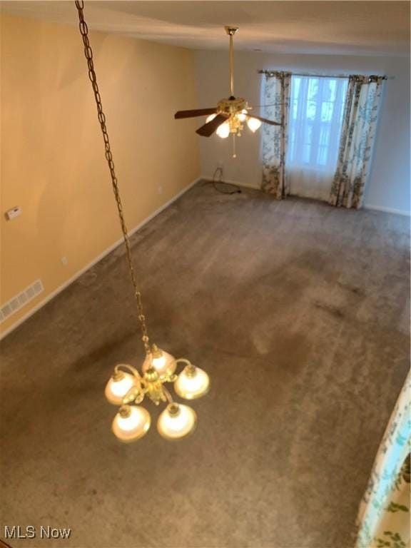 interior space featuring dark colored carpet and ceiling fan with notable chandelier