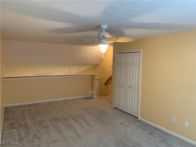 additional living space with carpet flooring, ceiling fan, lofted ceiling, and a textured ceiling