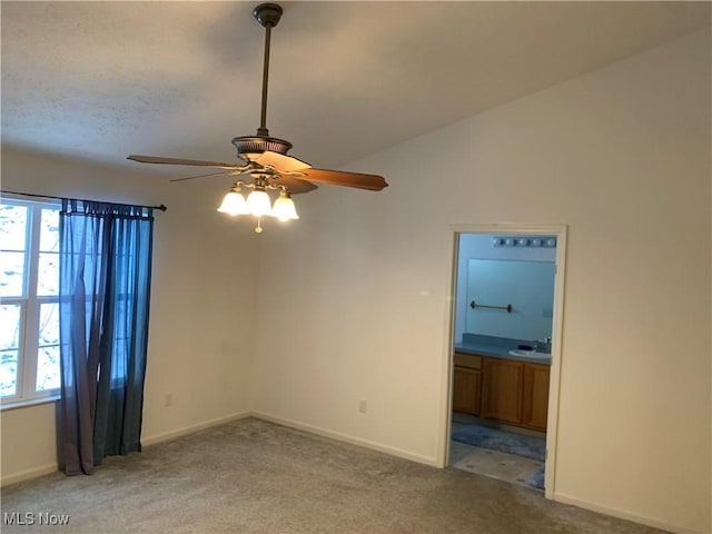 carpeted empty room featuring ceiling fan, sink, and lofted ceiling