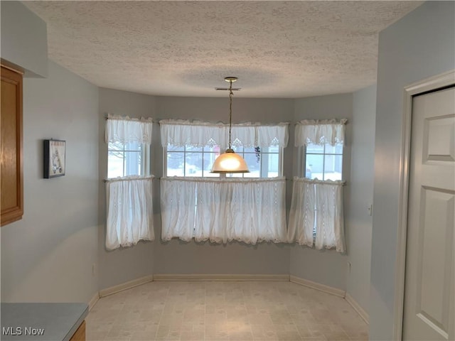 unfurnished dining area featuring a textured ceiling