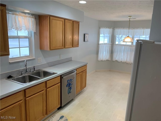 kitchen featuring dishwasher, white refrigerator, decorative light fixtures, and sink