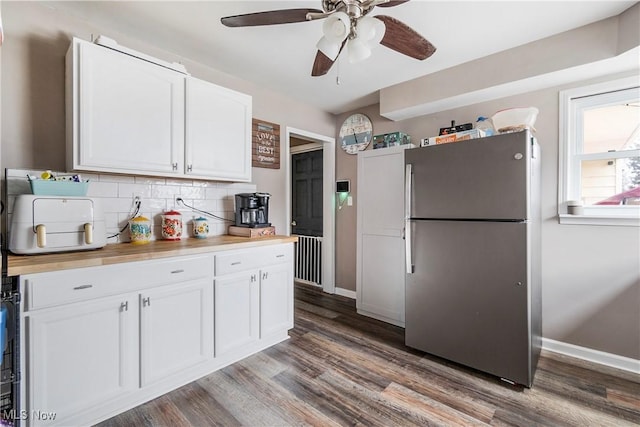 kitchen with dark hardwood / wood-style flooring, backsplash, ceiling fan, white cabinetry, and stainless steel refrigerator