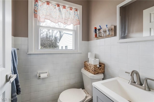 bathroom with vanity, toilet, and tile walls