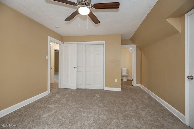 unfurnished bedroom featuring light carpet, a closet, vaulted ceiling, and ceiling fan