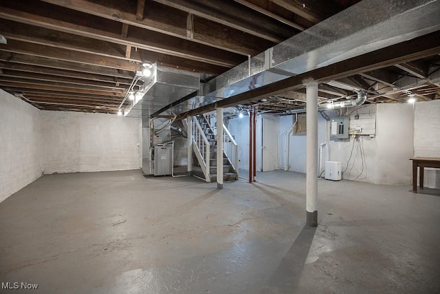 basement featuring electric panel and heating unit