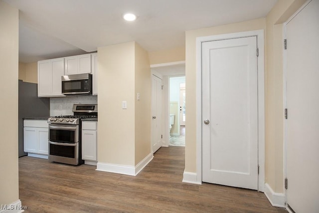 kitchen featuring tasteful backsplash, dark hardwood / wood-style flooring, white cabinets, and double oven range