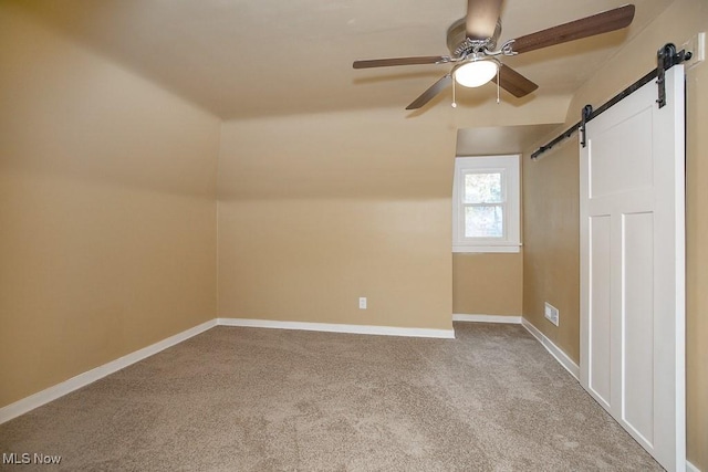 bonus room with a barn door, ceiling fan, light carpet, and vaulted ceiling