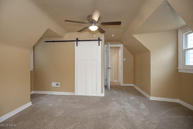 additional living space with a barn door, ceiling fan, light carpet, and lofted ceiling