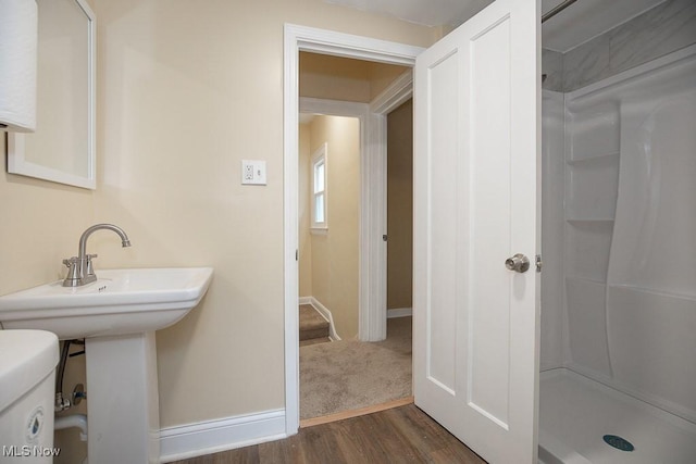 bathroom with hardwood / wood-style flooring, toilet, and walk in shower