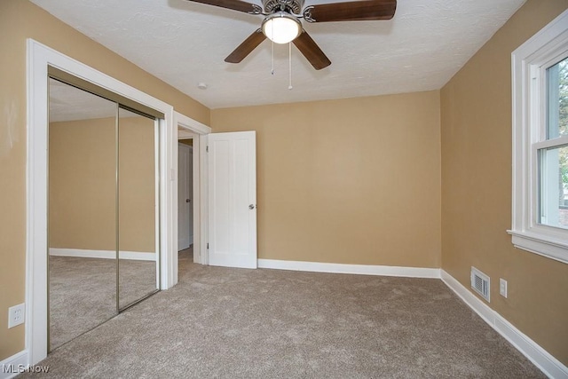 unfurnished bedroom featuring ceiling fan, light colored carpet, and a closet