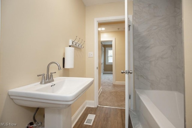 bathroom with hardwood / wood-style floors, a bathtub, and sink