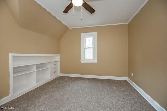 bonus room featuring built in shelves, ceiling fan, carpet floors, and vaulted ceiling