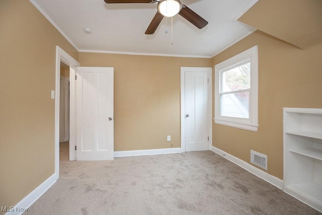 unfurnished bedroom with ceiling fan, crown molding, and light colored carpet