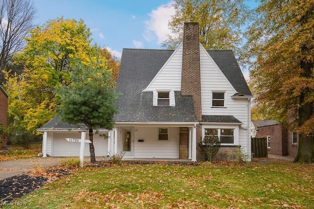 view of front of house with covered porch, a garage, and a front lawn