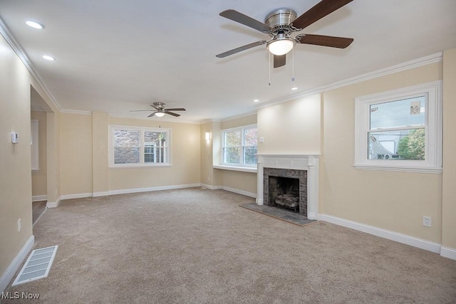 unfurnished living room with ceiling fan, light colored carpet, a fireplace, and crown molding