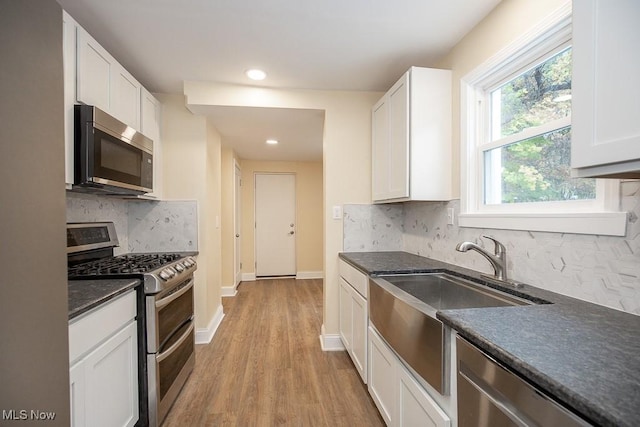 kitchen featuring appliances with stainless steel finishes, light hardwood / wood-style flooring, white cabinetry, and sink