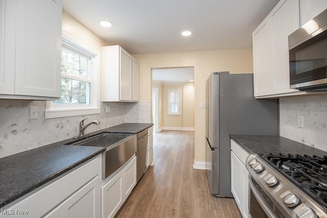 kitchen featuring sink, stainless steel appliances, tasteful backsplash, light hardwood / wood-style floors, and white cabinets