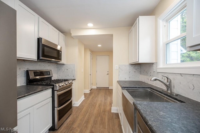 kitchen with light hardwood / wood-style floors, white cabinetry, appliances with stainless steel finishes, and tasteful backsplash